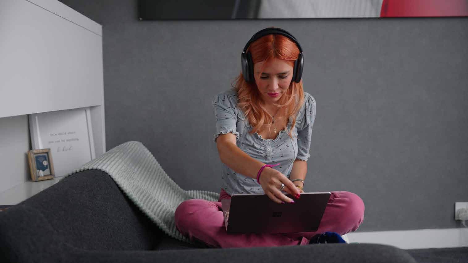 An Arden student in headphones working on a laptop