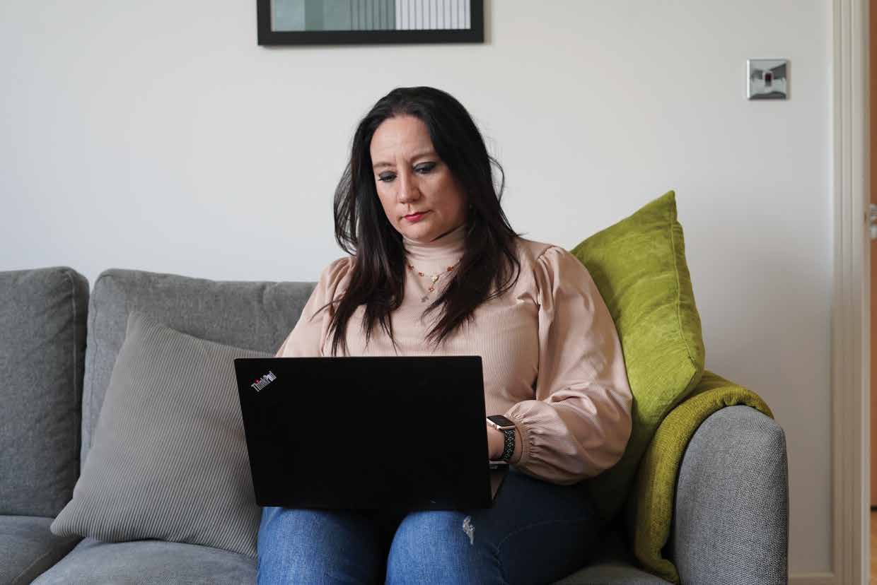 An Arden student working on a laptop on a sofa