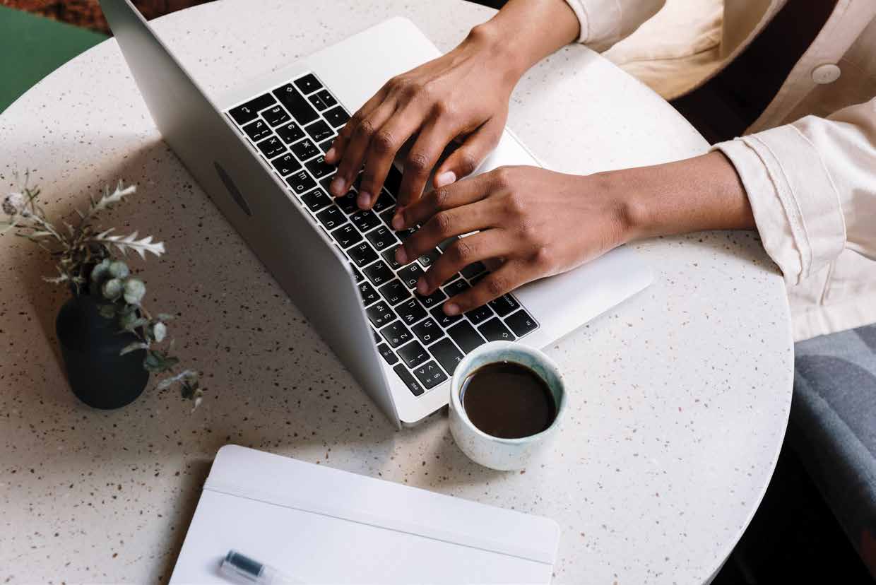 A student typing on a laptop beside a cup of coffee