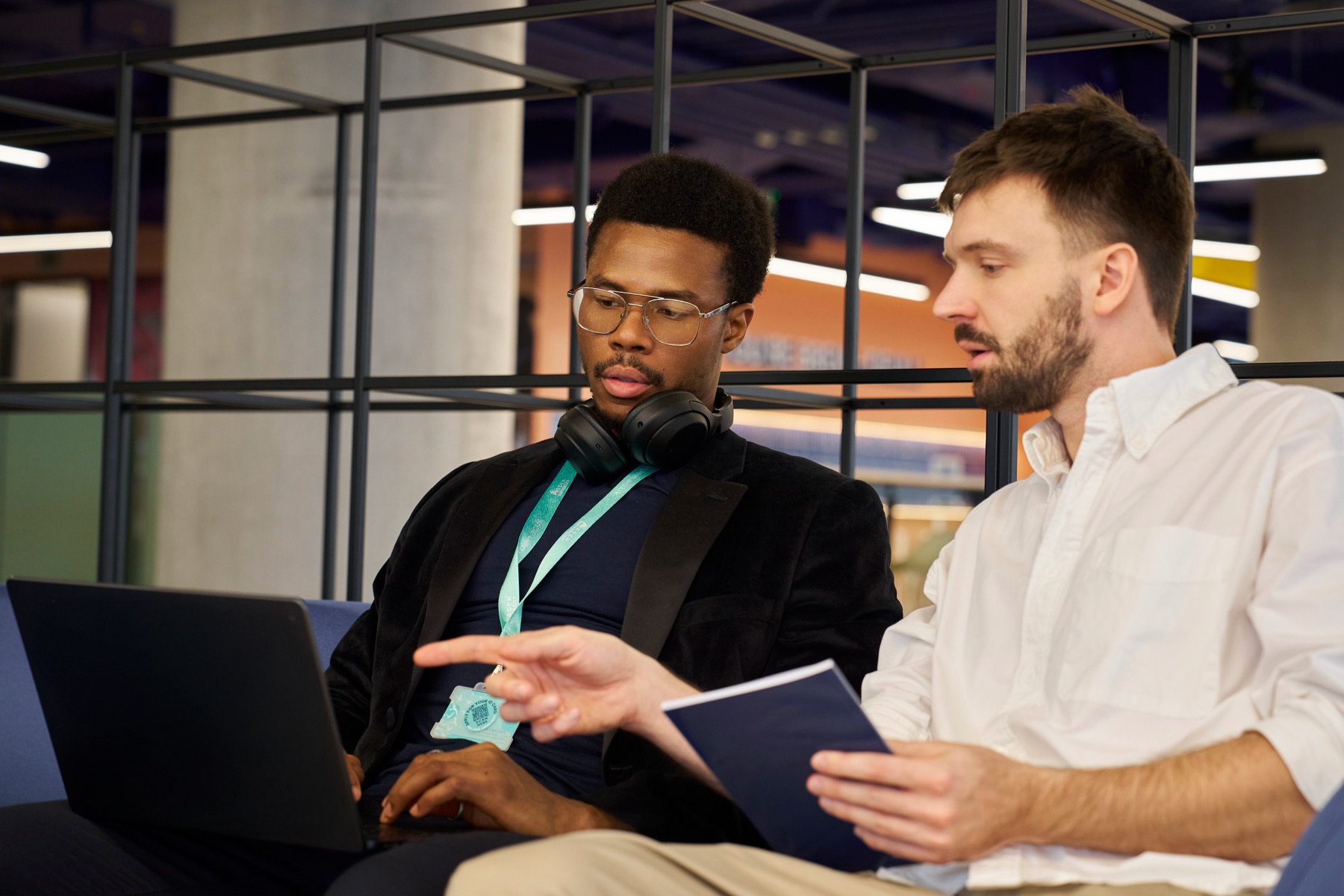 Two Arden students talking through notes on a sofa
