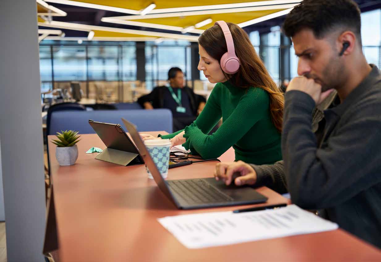 Two Arden students working on laptops in a study space